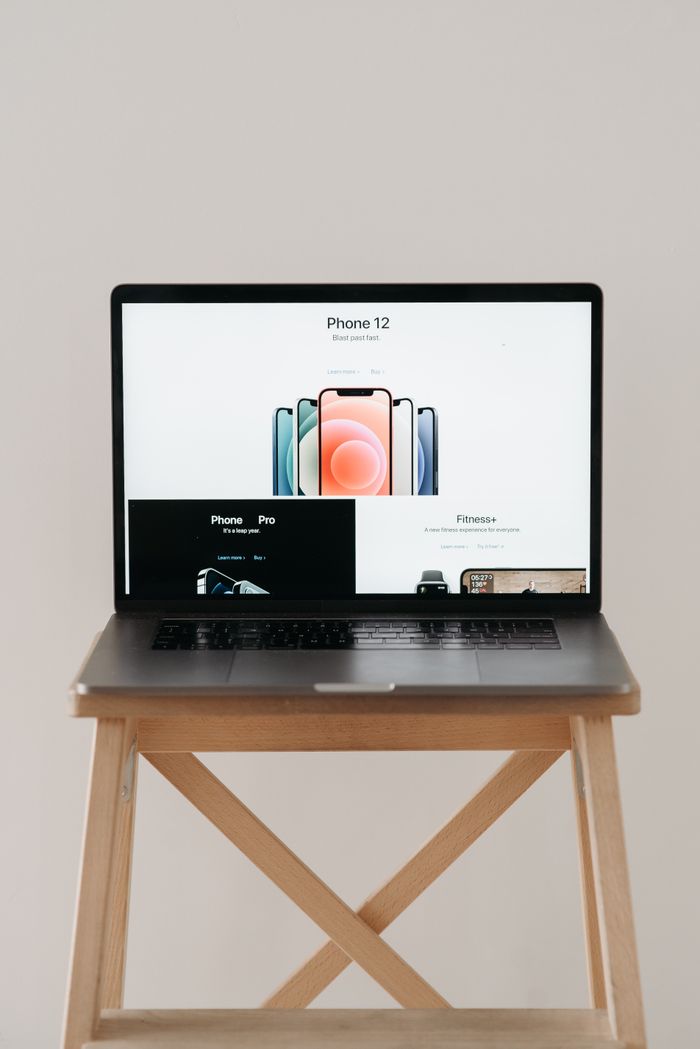 Home A sleek laptop on a wooden table showing a smartphone advertisement, perfect for tech and gadget content.